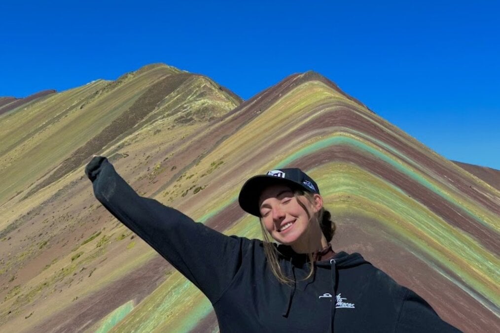 A traveler posing in front of colorful mountains in Peru